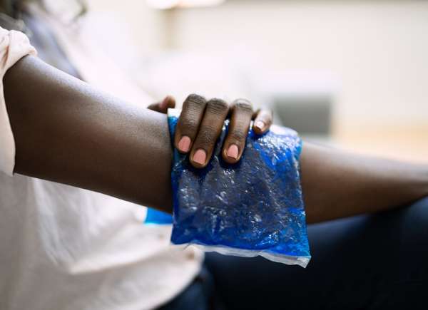 Femme noire appliquant une poche de glace sur son bras