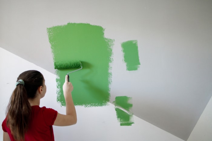 Fille peignant un mur en vert