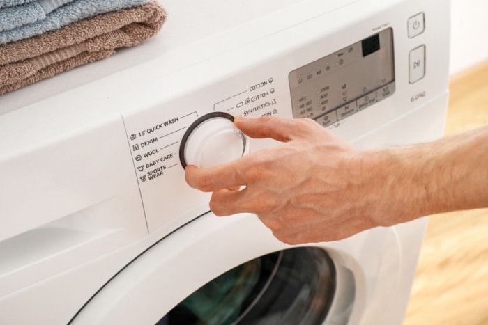 Gros plan d'une personne qui tourne le bouton d'une machine à laver. 