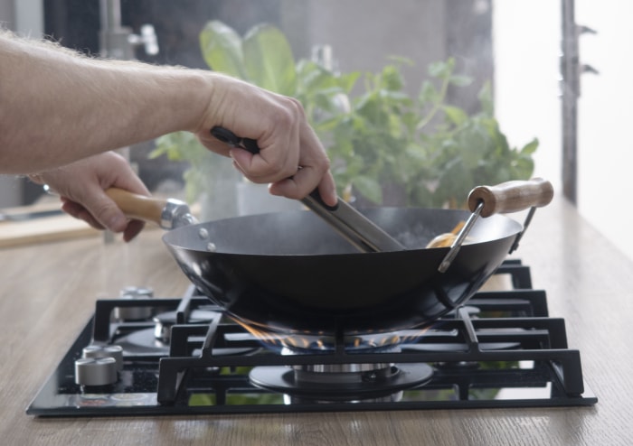 Poêle à frire sur une cuisinière à gaz. Le chef contrôle le processus de cuisson. Cuisson sur une cuisinière à gaz. Le gaz est cher en Europe.