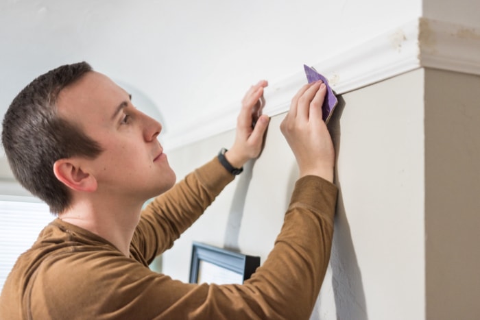 Homme examinant de petits trous dans une garniture murale.