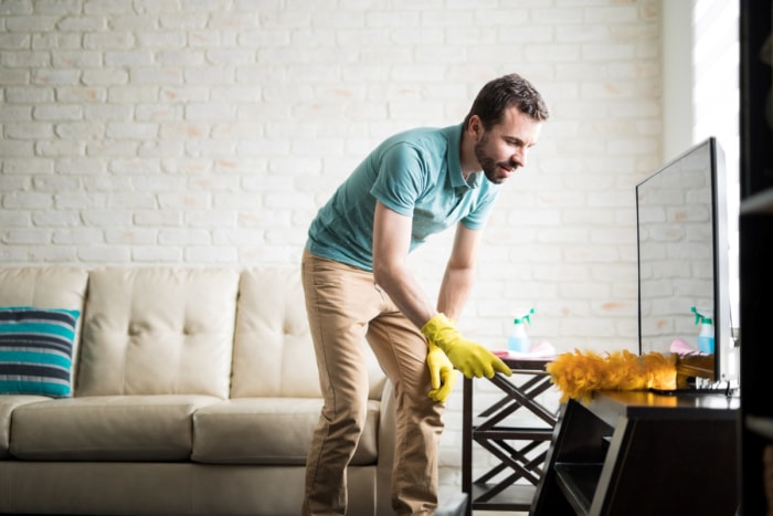 Homme utilisant un plumeau à la maison.