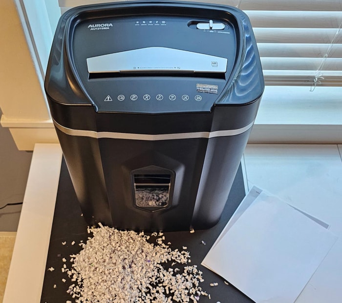 La meilleure option de destructeur de papier à côté d'une pile de papier et d'une pile de papier déchiqueté