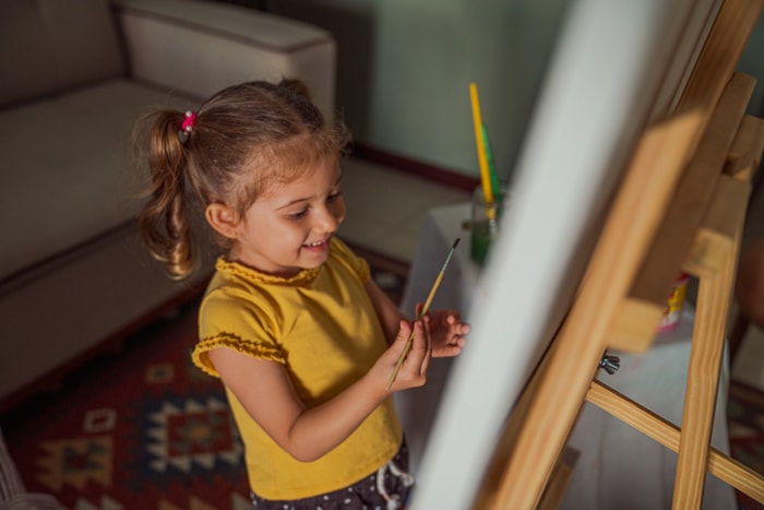 qu'est-ce qu'une salle de séjour une petite fille peignant sur un chevalet dans une salle de séjour avec un canapé