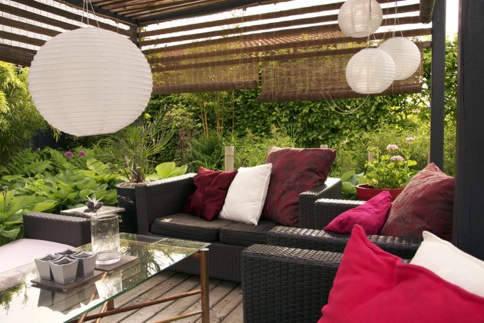 Pergola avec lampes, meubles de jardin et parasols pour plus d'intimité.