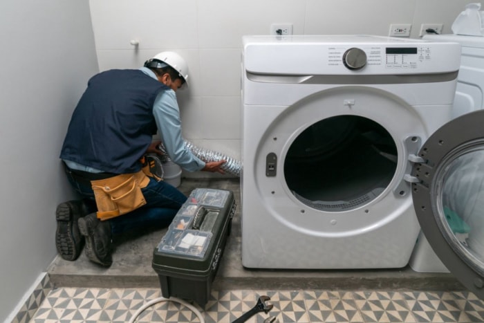 Un technicien répare une machine à laver. 