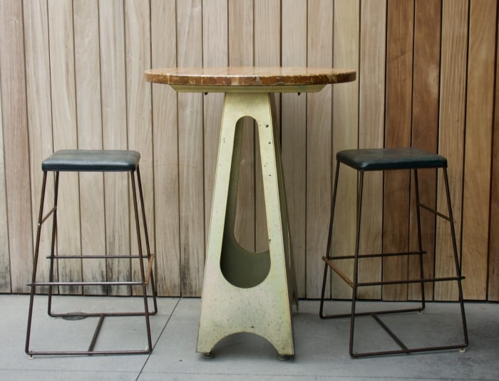 Une petite table à manger haute avec tabourets de bar.