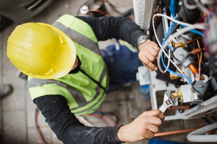 Générateur de secours iStock-1291724300 Le technicien en climatisation entretient l'unité de climatisation extérieure et le générateur à gaz