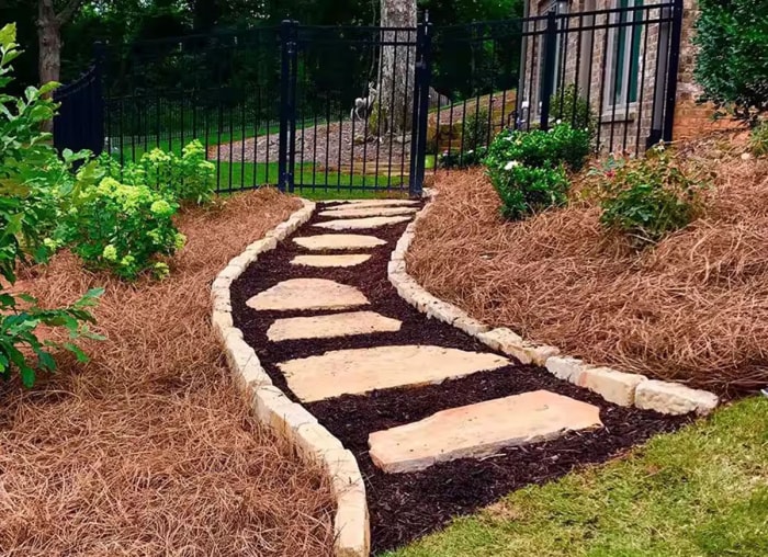 Un aménagement paysager avec des parterres de fleurs paillés avec du paillis de paille de pin.