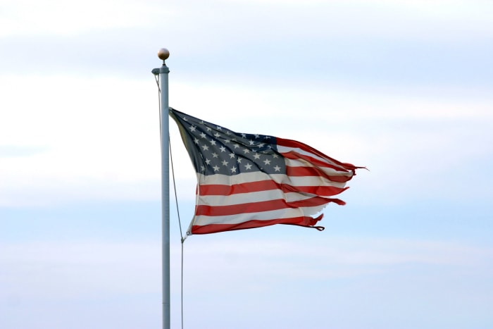 drapeau américain en lambeaux flottant contre un ciel bleu