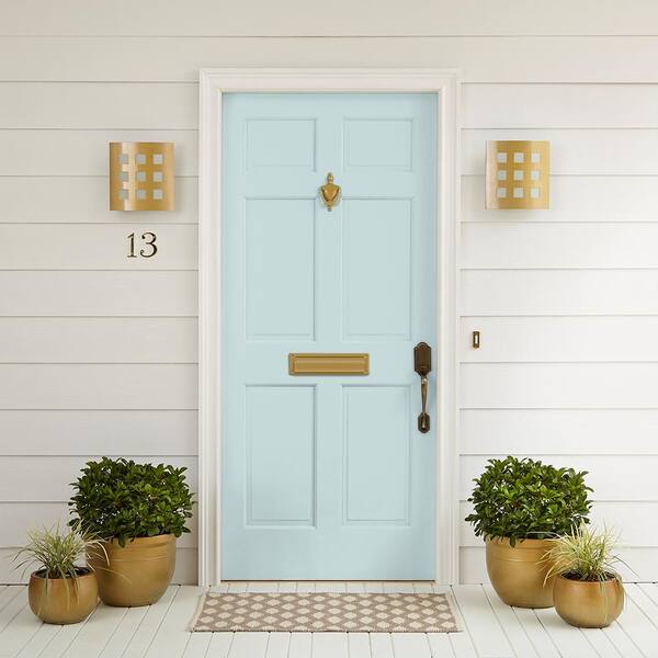 Sur le porche d'une maison blanche, deux plantes sont posées de part et d'autre d'une porte de couleur aqua pâle.