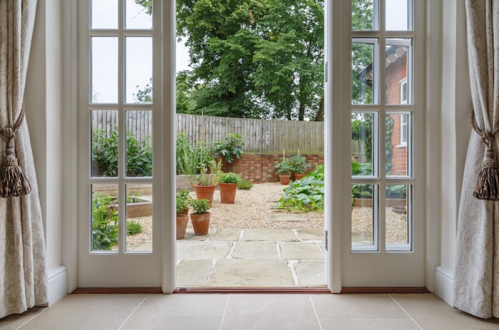 Les rideaux à pompons sont suspendus de part et d'autre d'une porte de patio menant à un jardin.