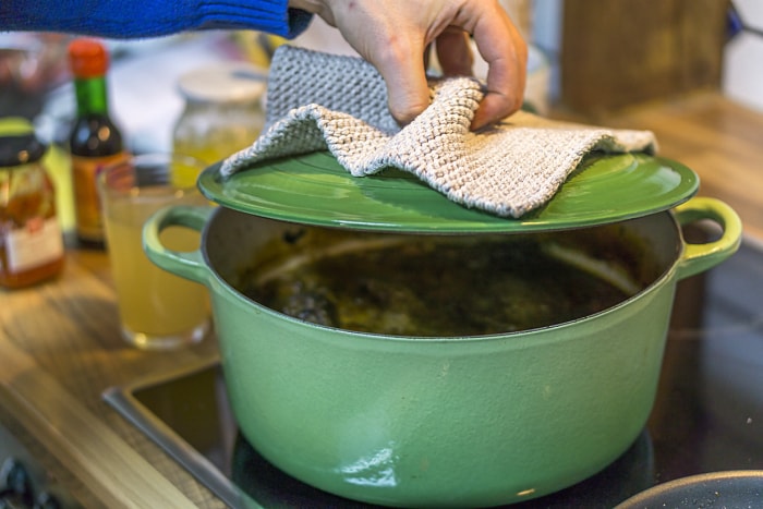 Marmite en émail vert sur la table de cuisson avec de la vapeur qui s'échappe.