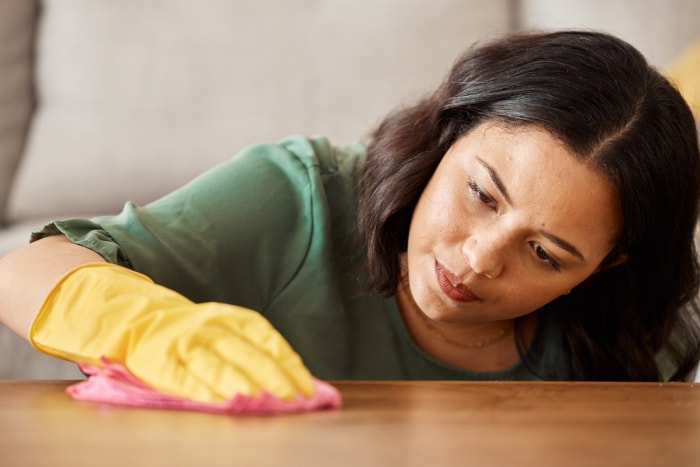 femme polissant une table basse en bois dans le salon