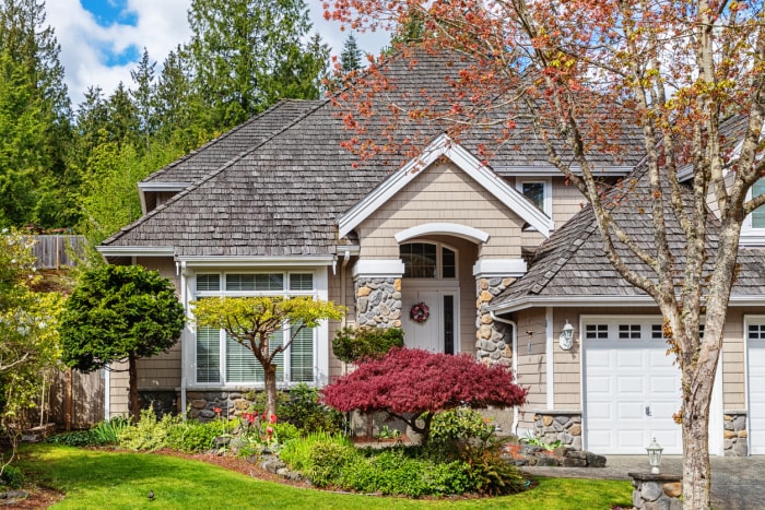 maison bronzée avec des arbres nains devant et une pelouse verte