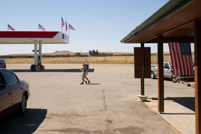 touristes marchant à l'extérieur d'une station-service et d'un musée avec des drapeaux américains sur le site de Little Bighorn à Garryowen, dans le Montana.