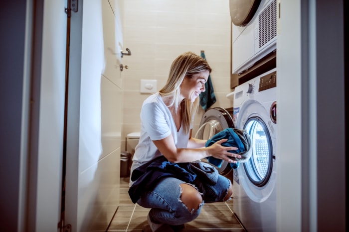 Femme mettant du linge dans le sèche-linge la nuit