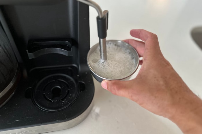 Quelqu'un fait mousser du lait à l'aide de la cafetière 4 en 1 Barista Bar de Cuisinart Coffee Center