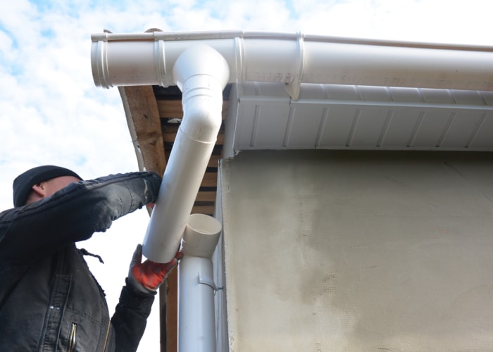 Un entrepreneur travaille sur le fascia, le soffite et les gouttières d'une maison.