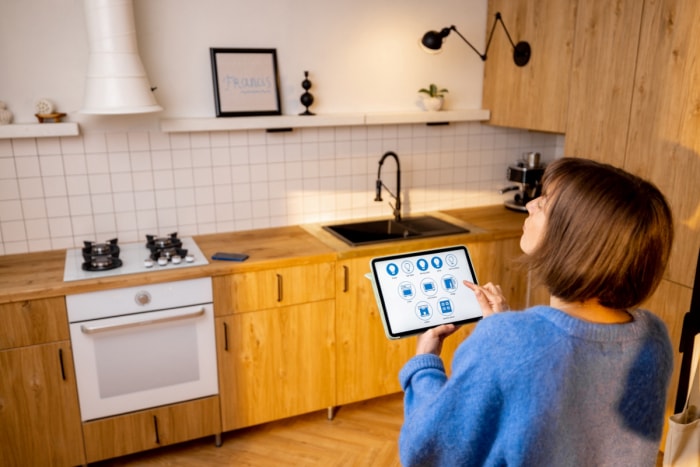 Femme utilisant une tablette pour contrôler les appareils de cuisine.