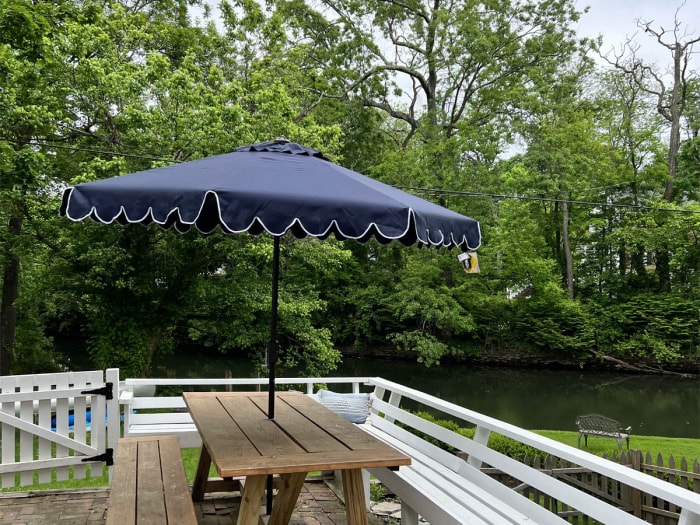 La meilleure option de parasols de terrasse est installée autour d'une table de pique-nique sur une terrasse qui donne sur une cour d'herbe verte bordée de grands arbres