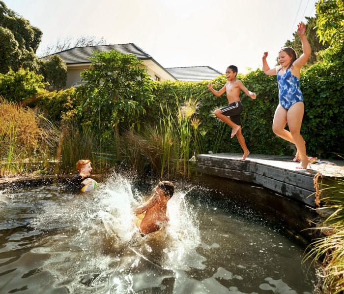 Enfants sautant dans une piscine naturelle.