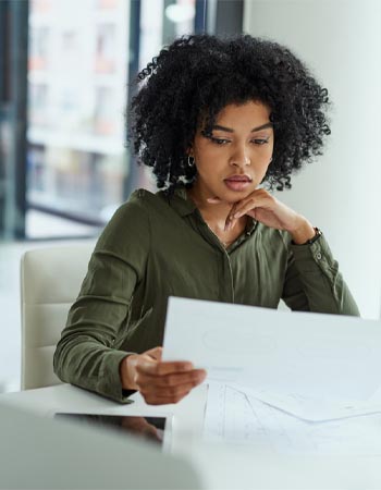 Une femme lit un document pensivement. 