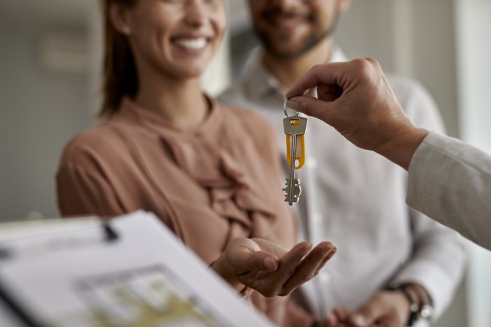 Gros plan d'un agent immobilier remettant les clés d'une nouvelle maison à un couple.