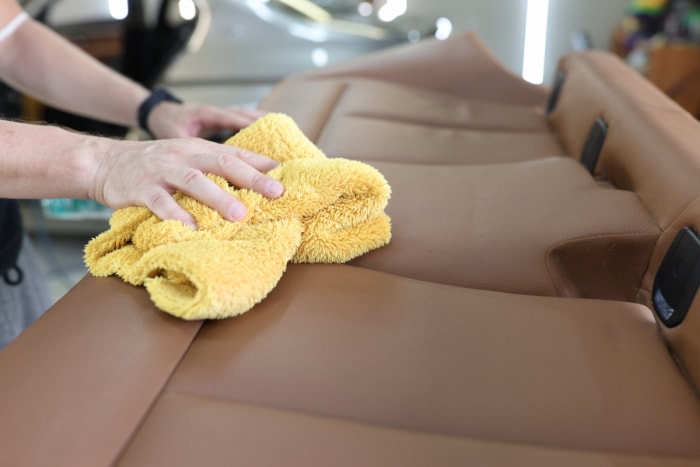 Nettoyer les sièges de voiture en cuir avec une serviette jaune.