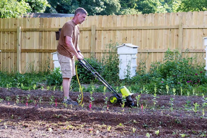 Un homme utilisant la meilleure option de motoculteur électrique dans un jardin