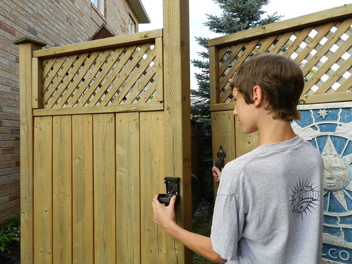 Un jeune utilise la meilleure option de loquet de portail pour ouvrir une porte dans une clôture