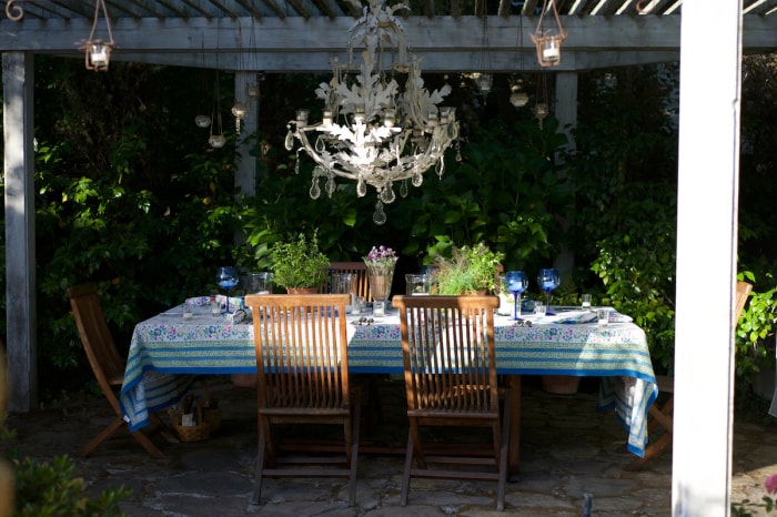 Une table dressée sous un gazebo avec lustre pour un dîner.