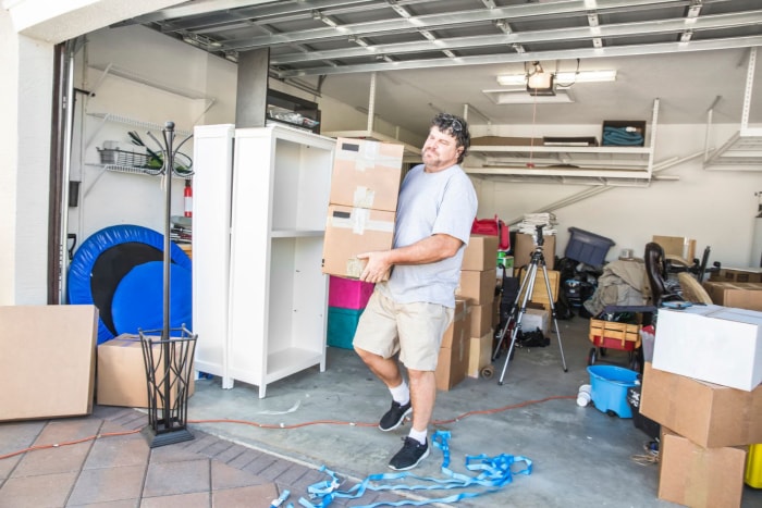 Un homme sort des cartons d'un garage.