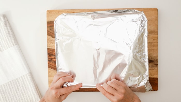 Personne utilisant du papier d'aluminium pour envelopper le plat de cuisson