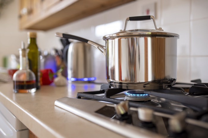 cuisinière à gaz allumée avec une casserole dessus