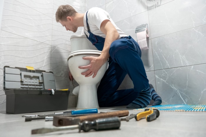 Professionnel installant de nouvelles toilettes avec des outils sur le sol.