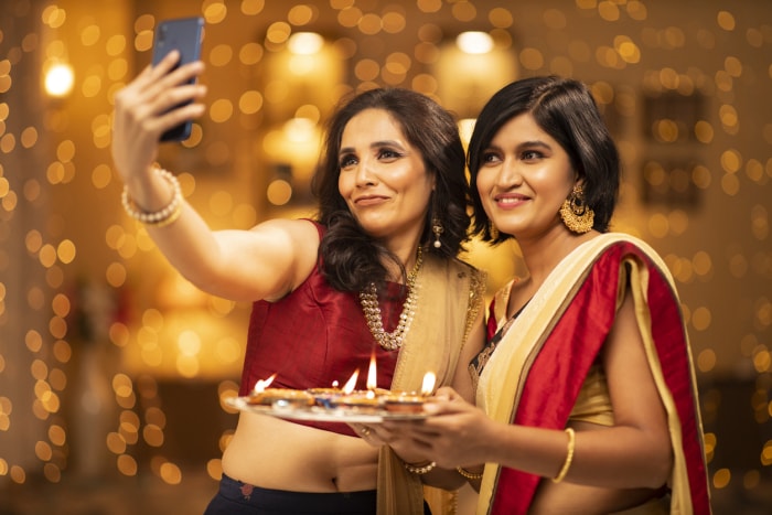 deux-femmes-en-saris-prennent-un-selfie-devant-les-lumières-du-rideau-ficelé-à-la-partie-diwali