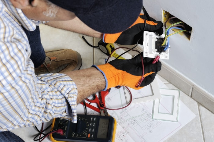 iStock-894986152 gants de travail électricien travaillant sur une prise