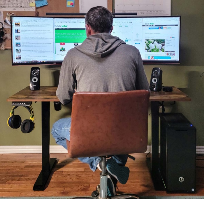 Un homme est assis et travaille sur un ordinateur au bureau debout de Fezibo