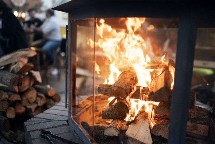 comment nettoyer une cheminée cheminée à bois avec des flammes vives pile de bûches à proximité