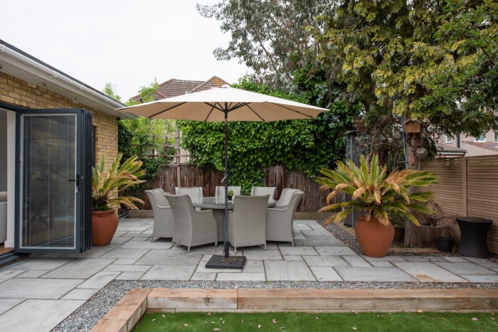 Patio en ciment dans la cour arrière avec table et parasol. 