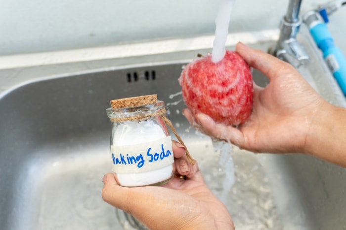 Femme lavant une pomme rouge avec du bicarbonate de soude