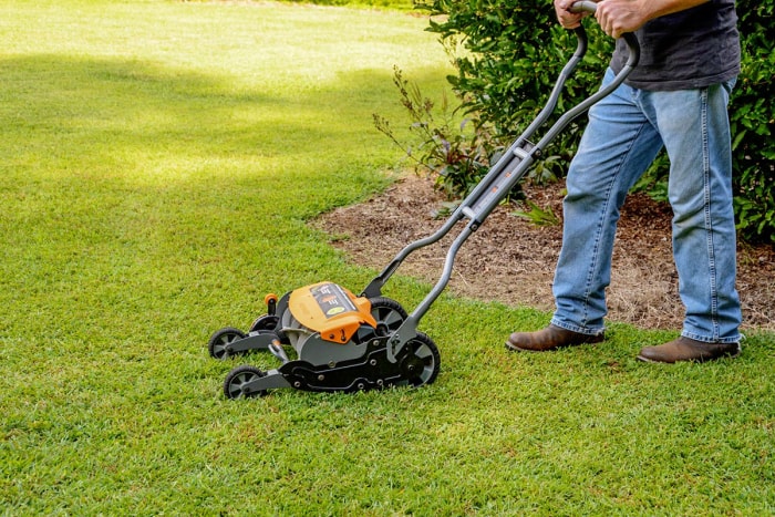 Une personne utilisant la tondeuse à bobine Fiskars StaySharp Max pour tondre sa pelouse