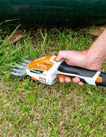 La cisaille de jardin sans fil Stihl avec coupe-herbe intégré permet de couper l'herbe.