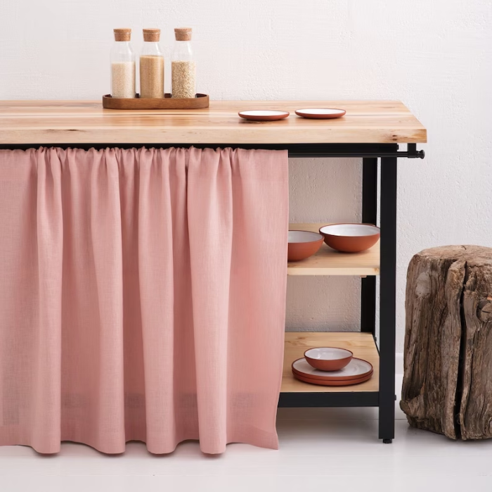 Une petite table d'appoint de cuisine recouverte d'un rideau rose.