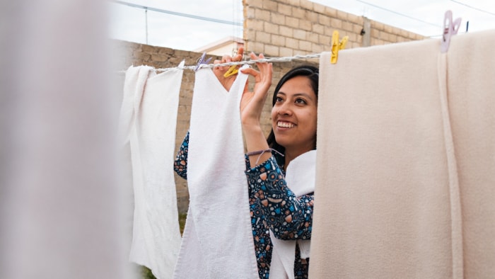 Portrait d'une jeune femme souriante, linge suspendu dans une cour