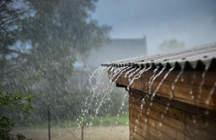 La pluie coule d'un toit en métal gris. 