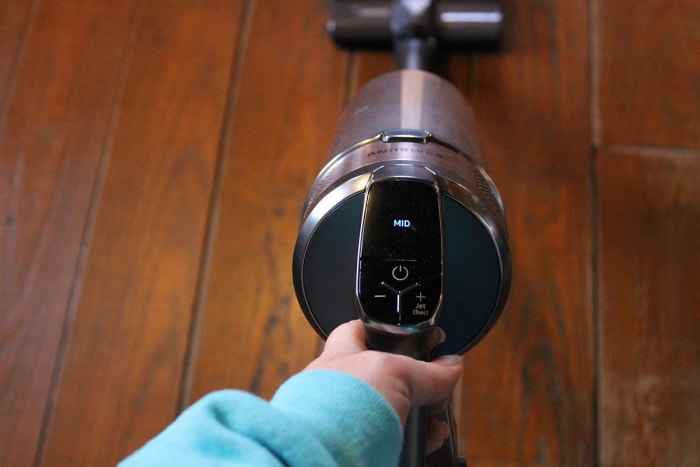 Personne passant l'aspirateur sur un plancher de bois franc avec l'aspirateur léger Samsung Jet 75 Pet