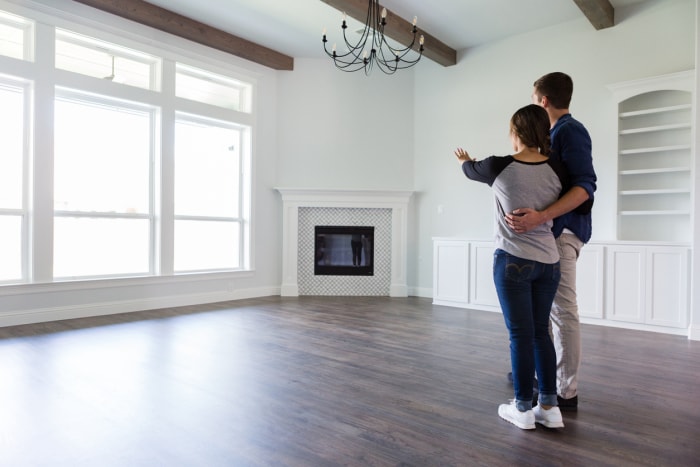 Vue arrière d'un jeune couple planifiant la décoration du salon de leur nouvelle maison.