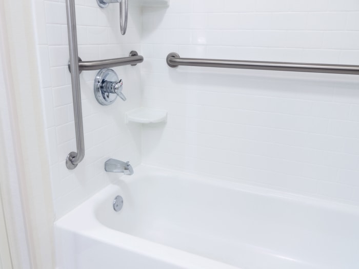 salle de bain accessible avec barres d'appui dans la douche.